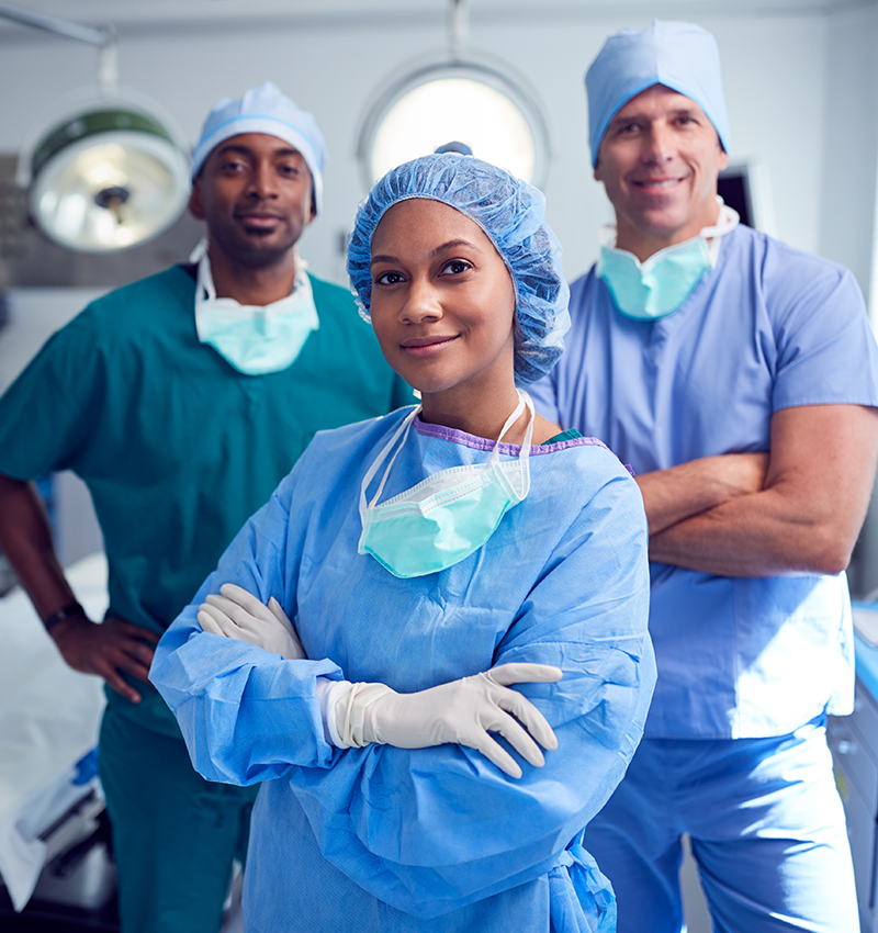 A surgical team including a surgeon, a CRNA and an anesthesiologist standing together in an operating room