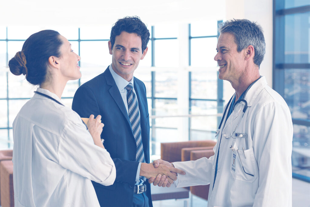 A locum staffing recruiter shaking hands with a medical provider and talking with a second locum tenens physician