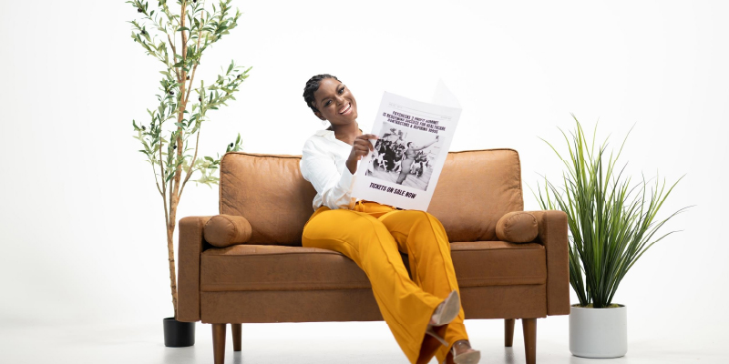 woman sitting on a couch while holding a newspaper against a white background